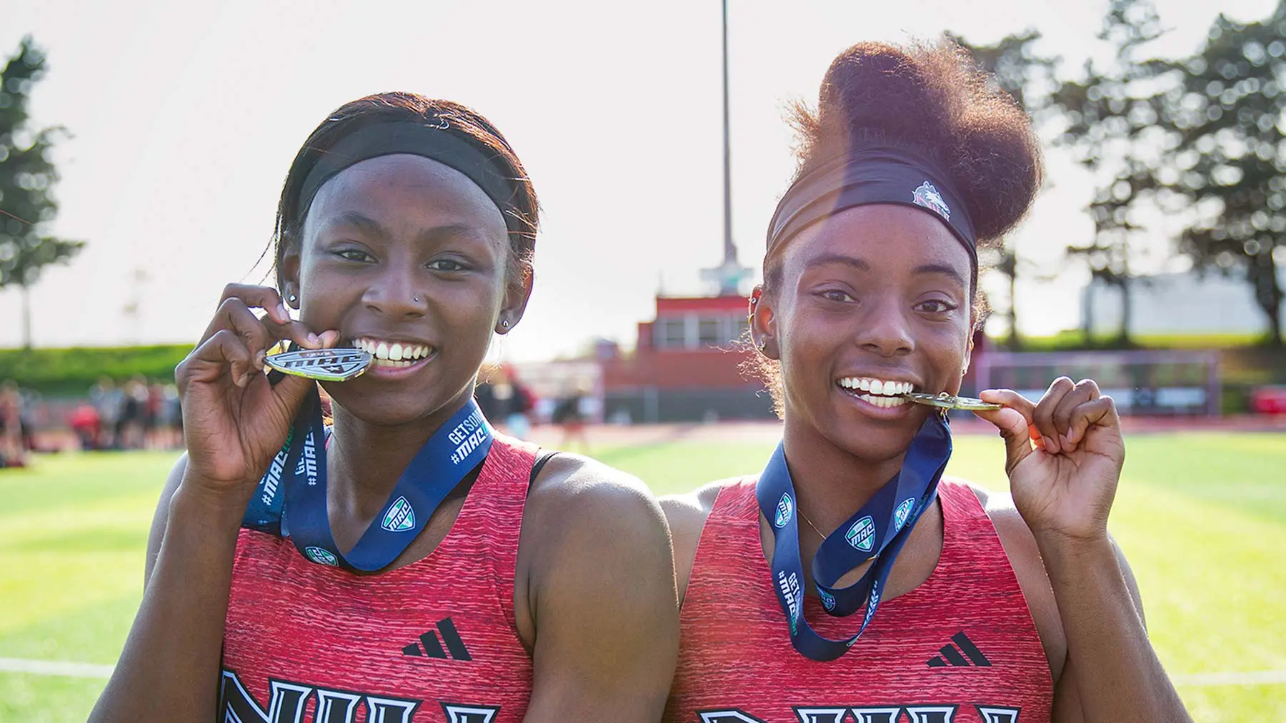 track athletes biting their medals